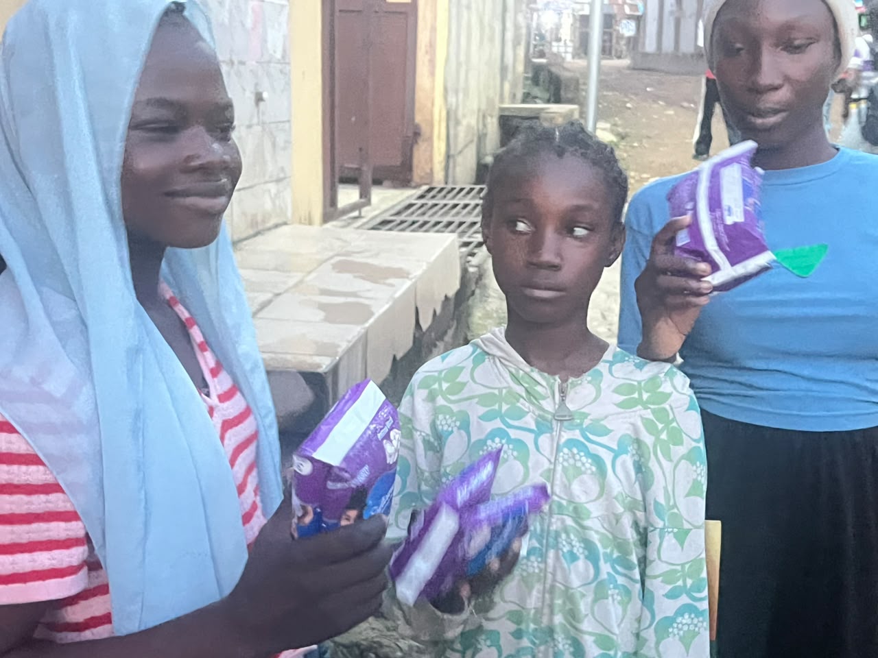A recipient holding sanitary pads distributed during the Apa outreach